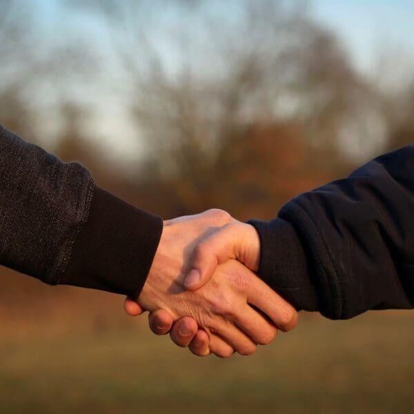 Two people shaking hands in a field.